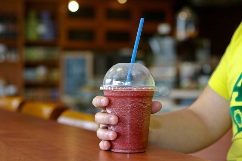 someone-holding-a-frozen-beverage-smoothie-on-top-of-the-table@2x