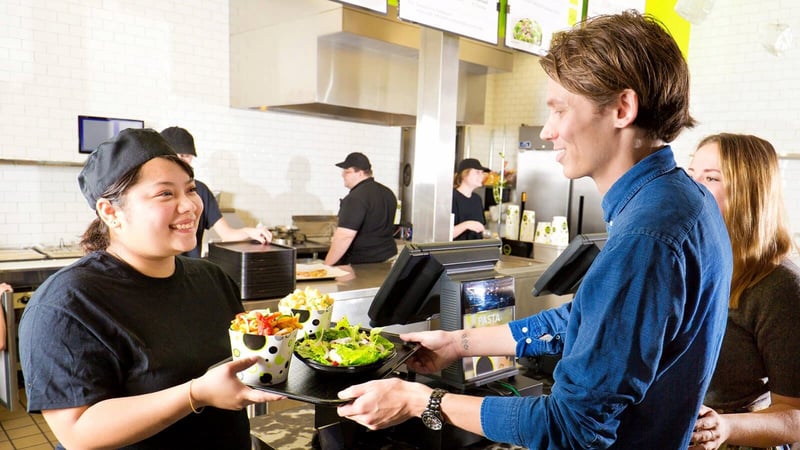 FBD Frozen. Quick service restaurant worker hands customer their food.
